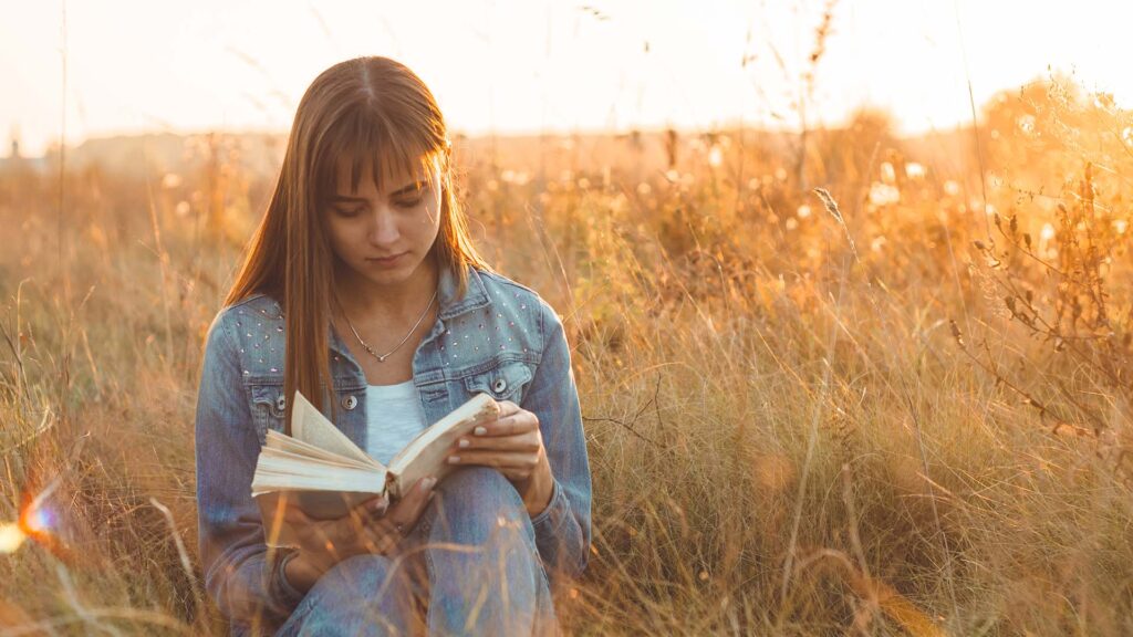 Jonge vrouw die buiten een boek leest